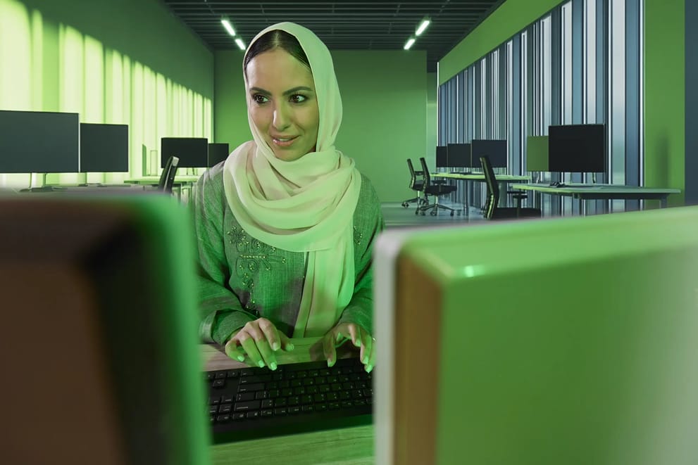 Woman working on a computer in a modern office typing on a keyboard, using Salam 5g connectivity.